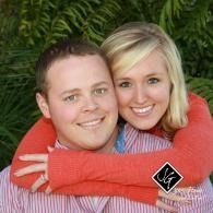 Smiling couple embracing outdoors against a leafy green backdrop
