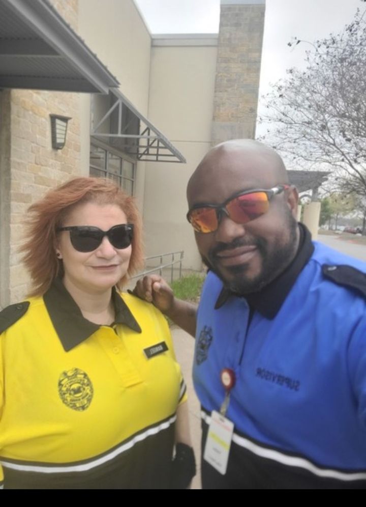 Two people in sunglasses wearing bright uniforms pose outside a building.