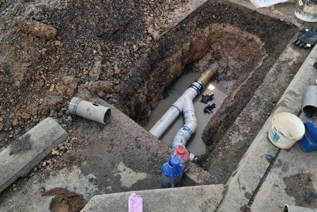 A Pipe Is Laying In The Dirt In A Hole — Bay City Plumbing in Torquay, QLD