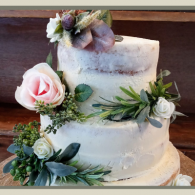 Three-tier white wedding cake with pale pink and purple flowers and greenery decorations