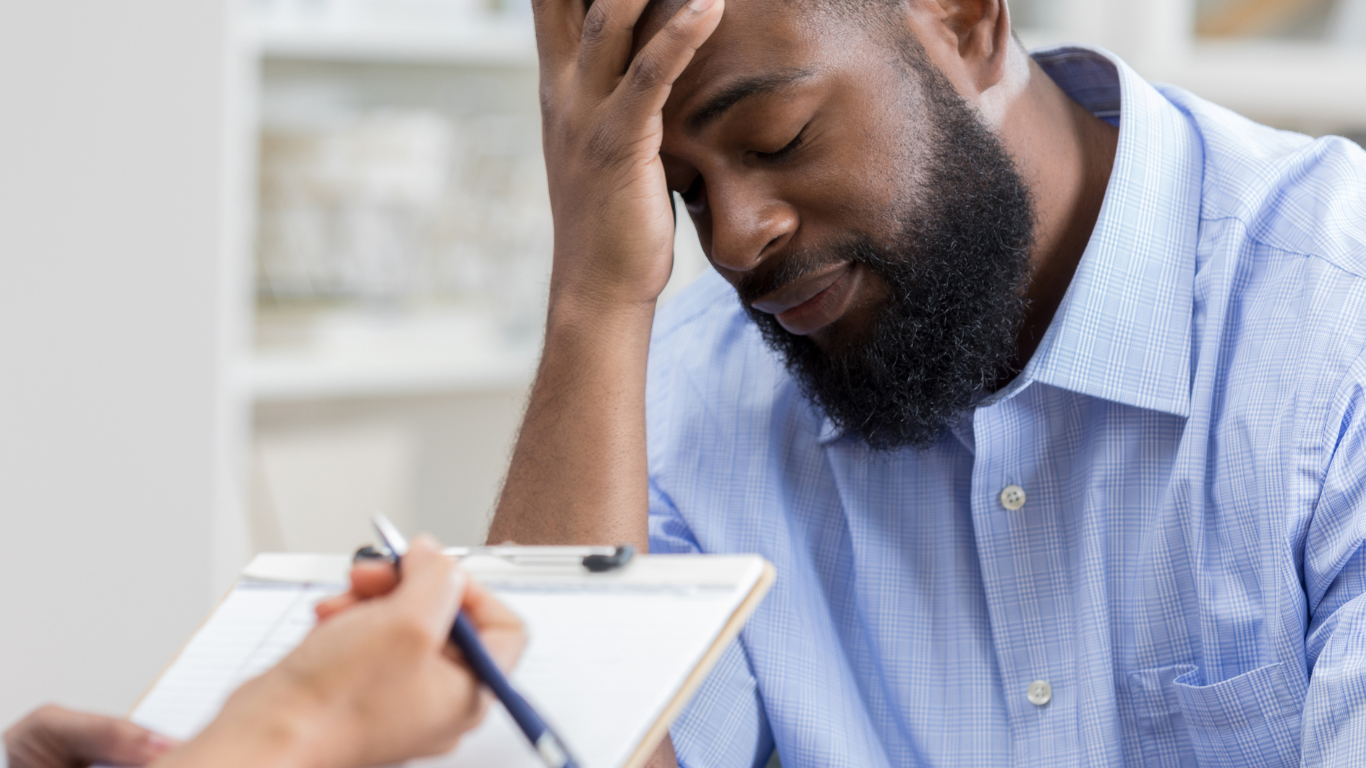 Man holding his head while speaking with a therapist during a counseling session