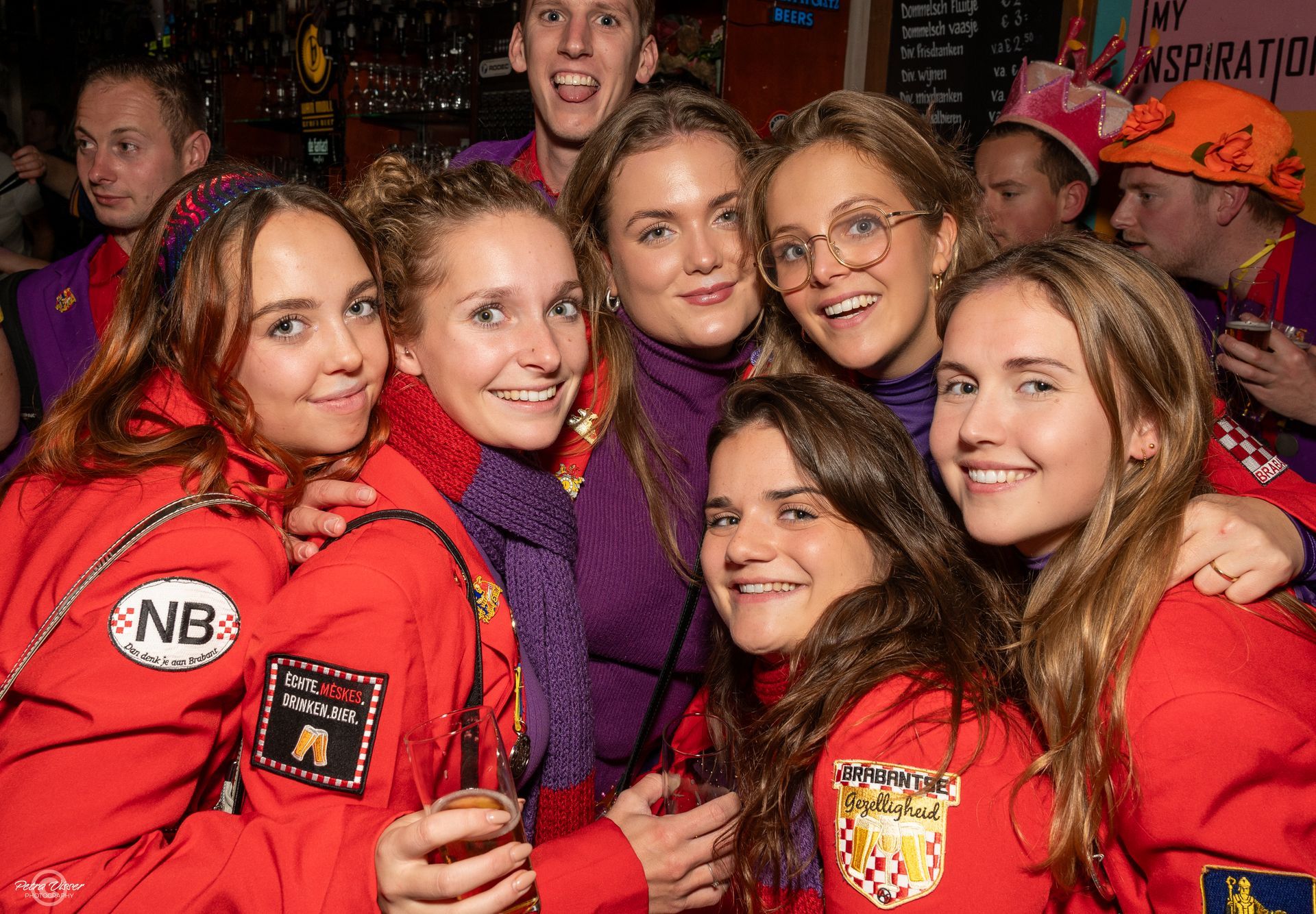 Een groep jonge vrouwen in rode jasjes poseert voor een foto.