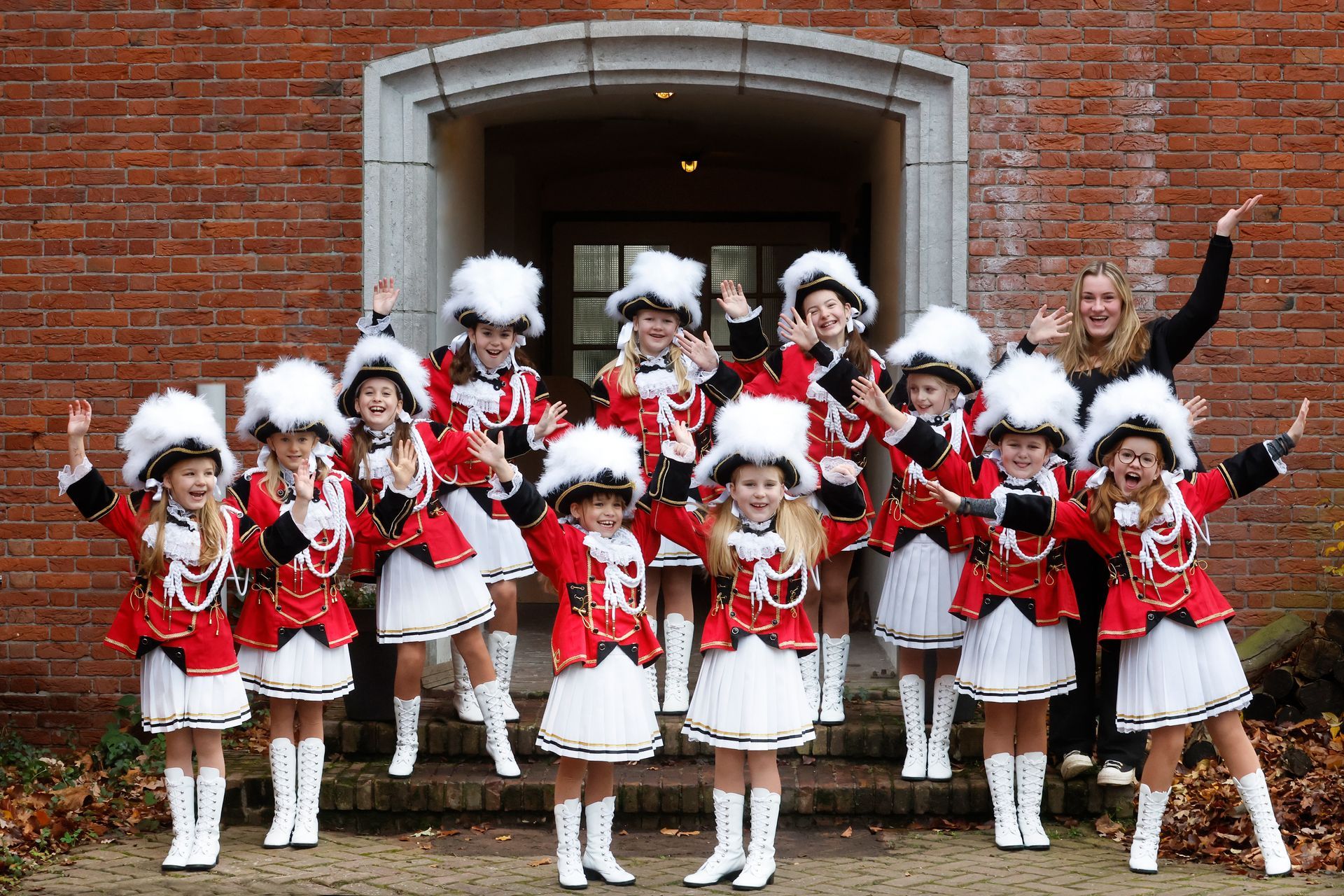 Een groep cheerleaders poseert voor een foto voor een bakstenen gebouw