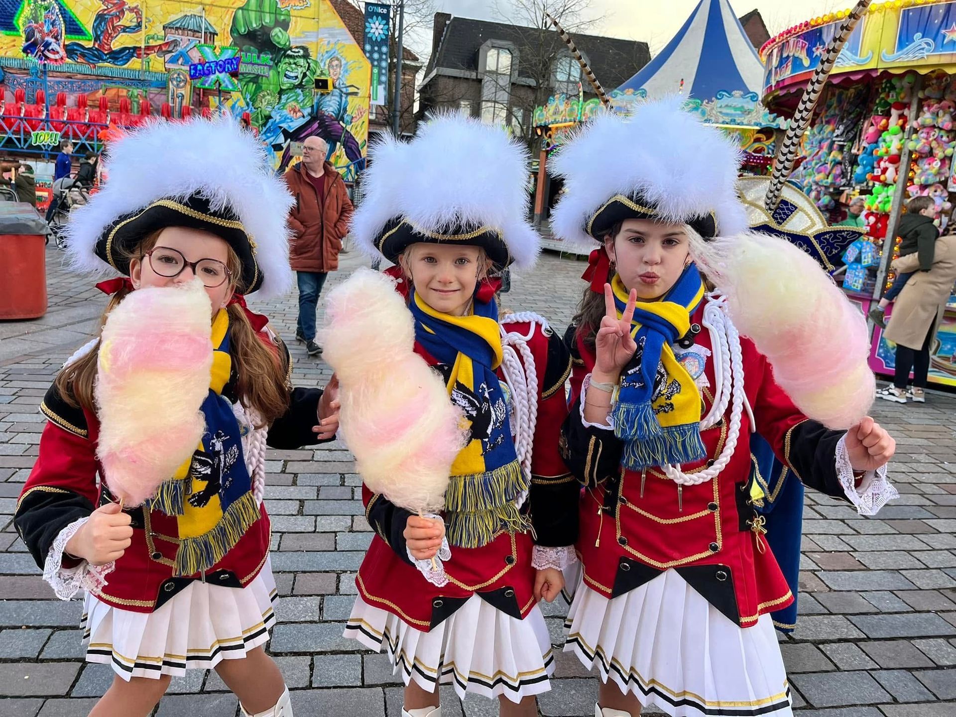 Drie kleine meisjes in kostuums houden suikerspin in hun handen.