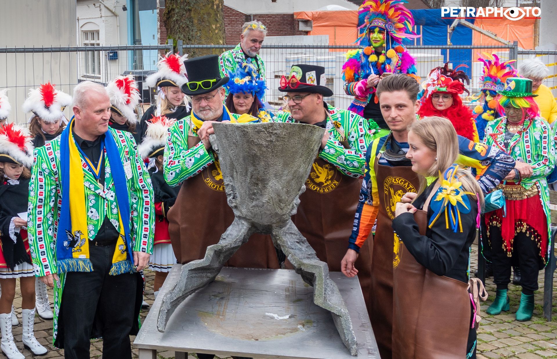 Een groep mensen in kleurrijke kostuums staat rond een groot object.