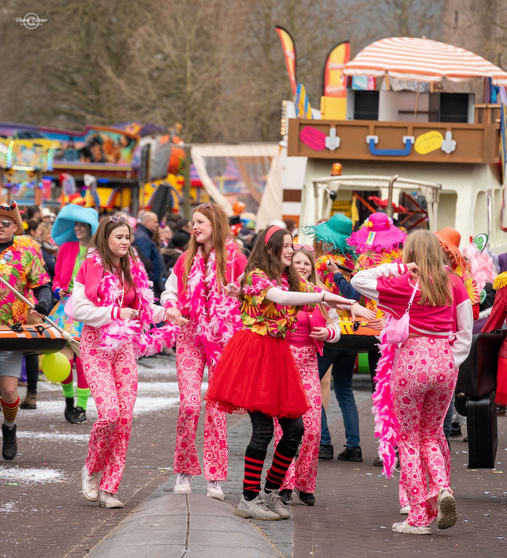 Een groep mensen in roze kleding loopt door een straat.