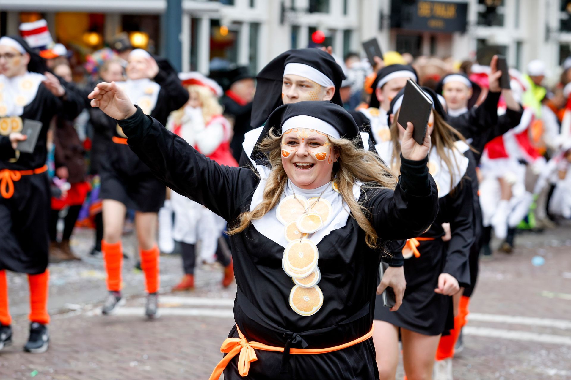 Een groep mensen, gekleed als nonnen, danst in een parade.