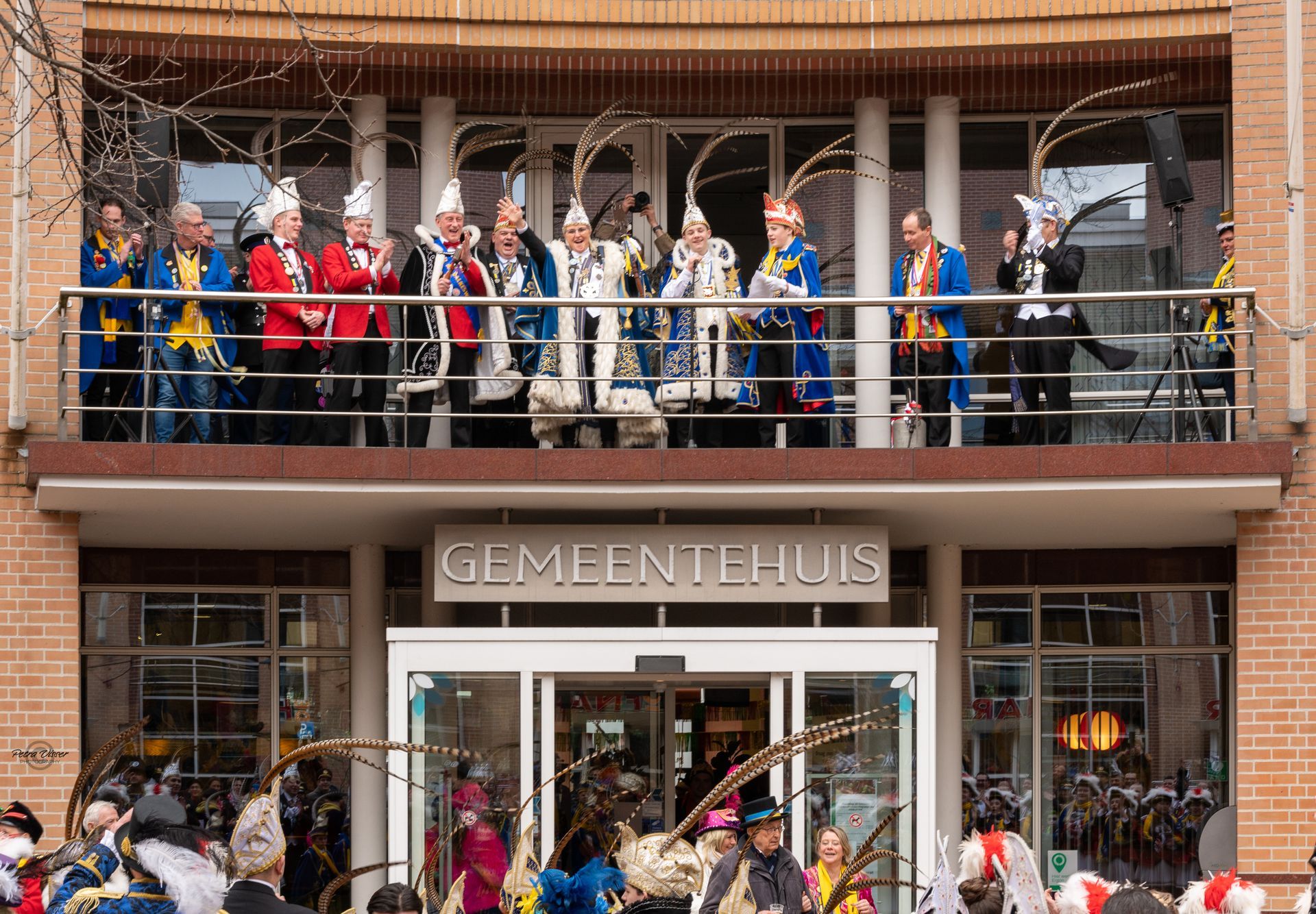 Een groep mensen staat op een balkon voor een gebouw.