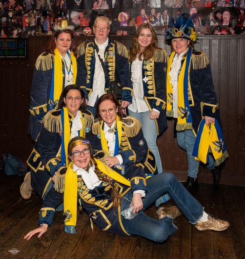 Een groep vrouwen poseert voor een foto en een van hen draagt een jas met de tekst 'tivoli' erop