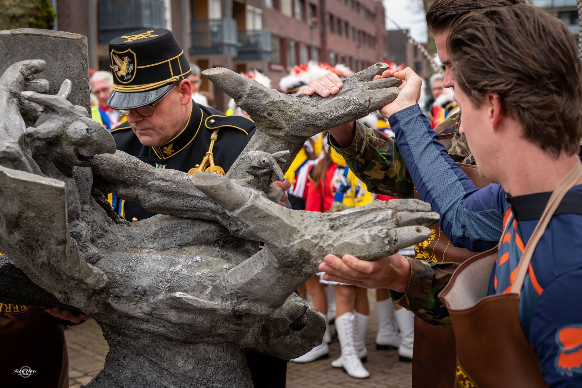 Een groep mannen staat rond een standbeeld.