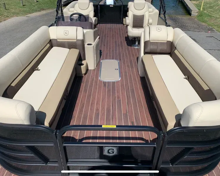 Pontoon boat interior with light and dark brown flooring, beige and brown seating, and black accents.