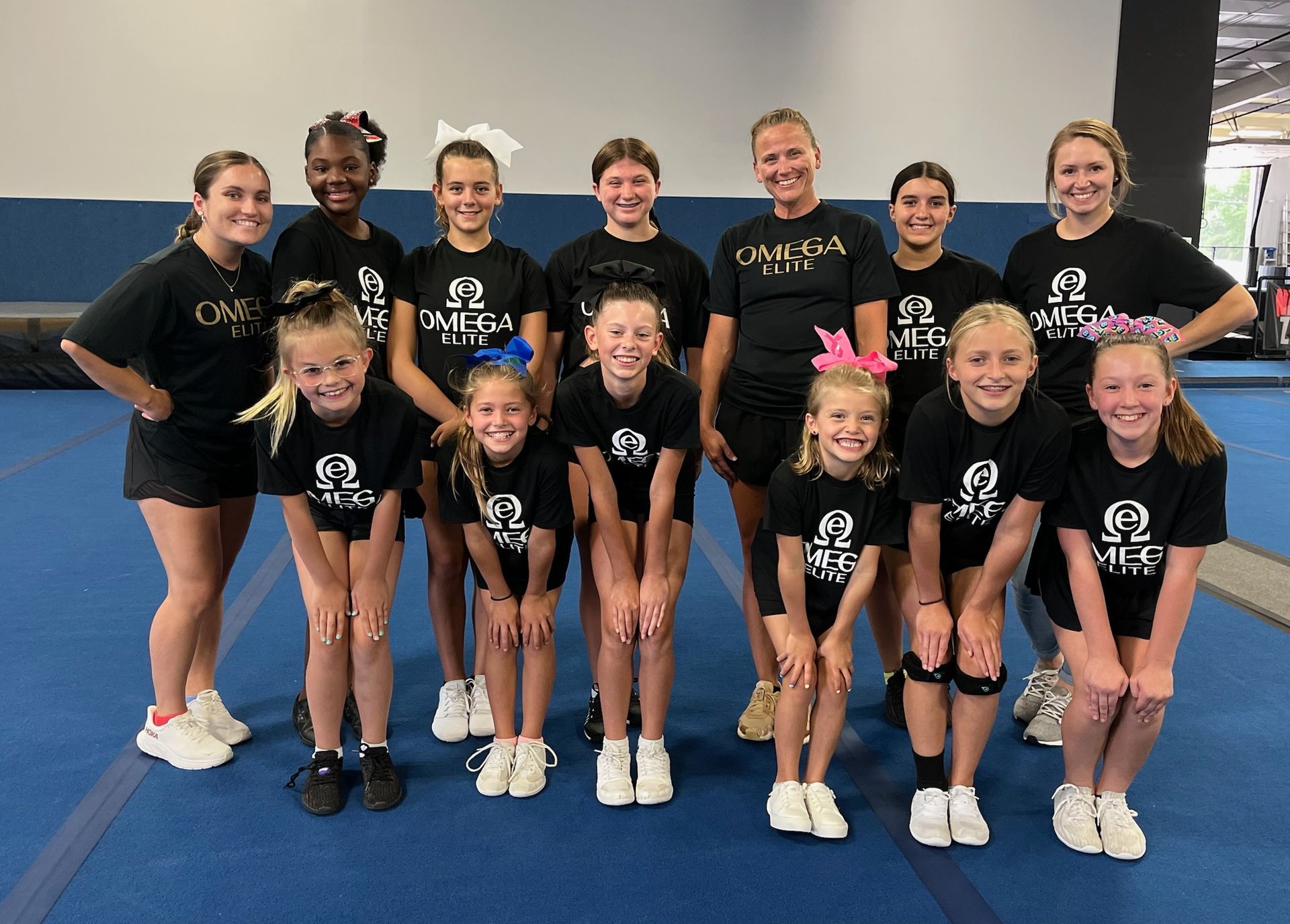 A group of cheerleaders are doing a pyramid in a gym.