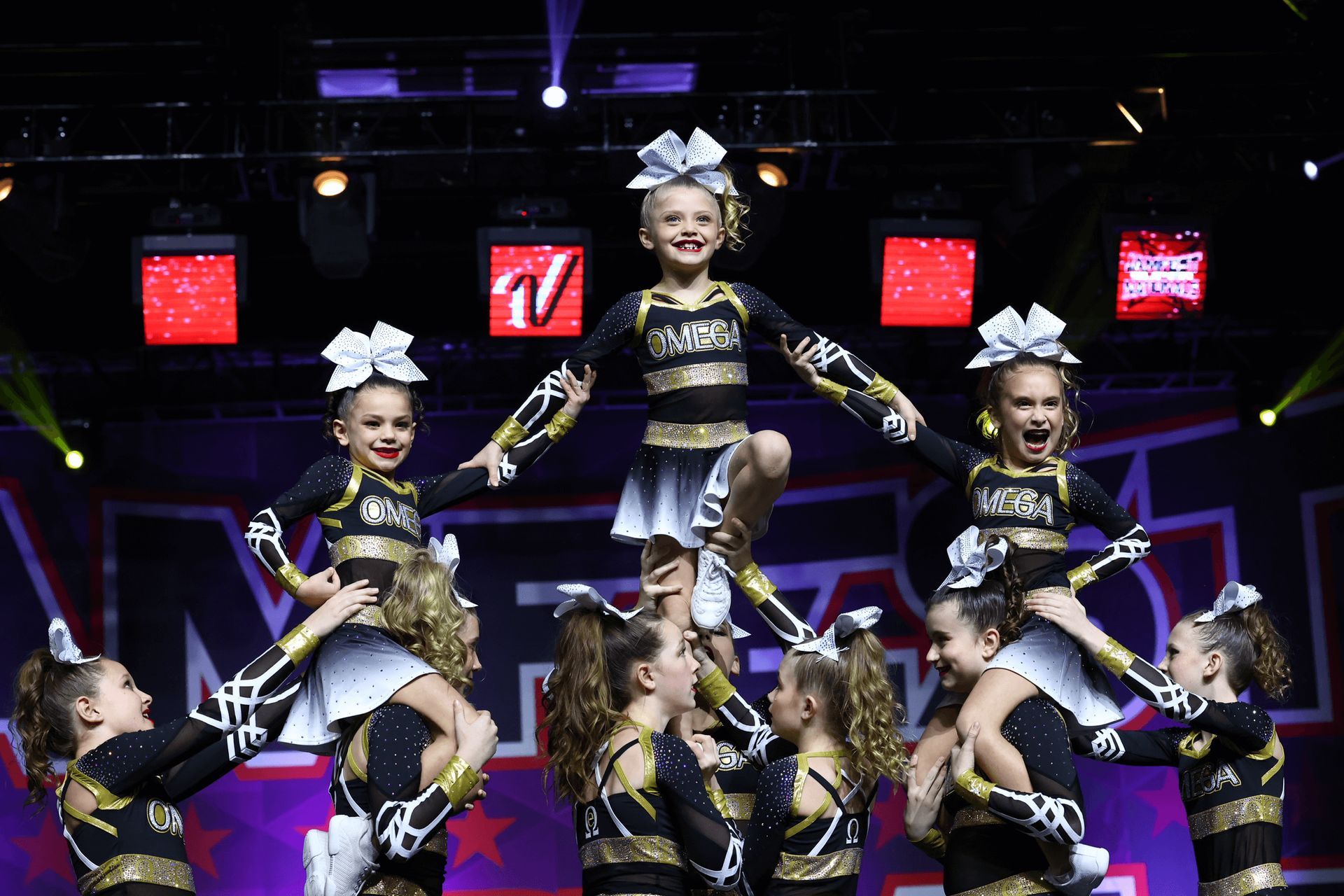 A group of cheerleaders are doing a pyramid in a gym.