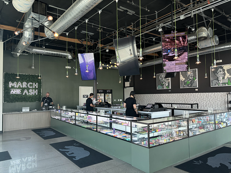Interior of March and Ash dispensary: sales counter, display cases, staff, product, green and black decor.