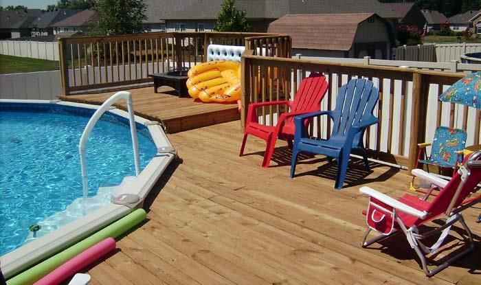 A wooden deck with a swimming pool in the background
