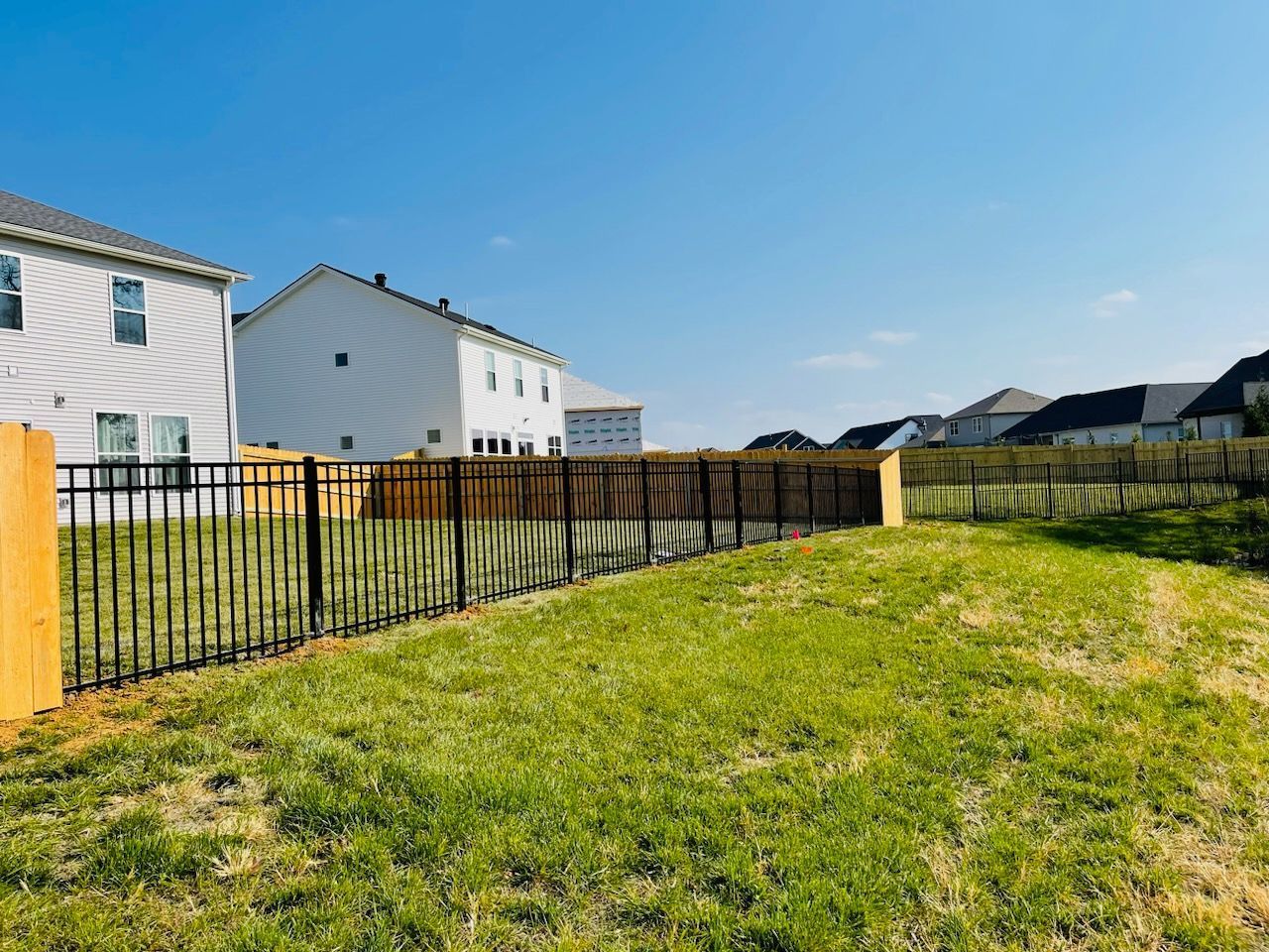 A backyard with a fence and a house in the background.