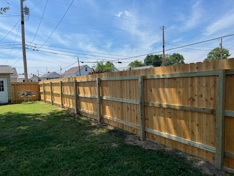 A wooden fence is in the backyard of a house.