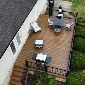 An aerial view of a wooden deck with a table and chairs and a grill.