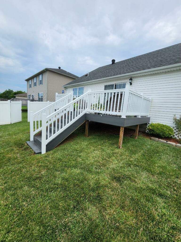 A white house with a deck and stairs in the backyard.
