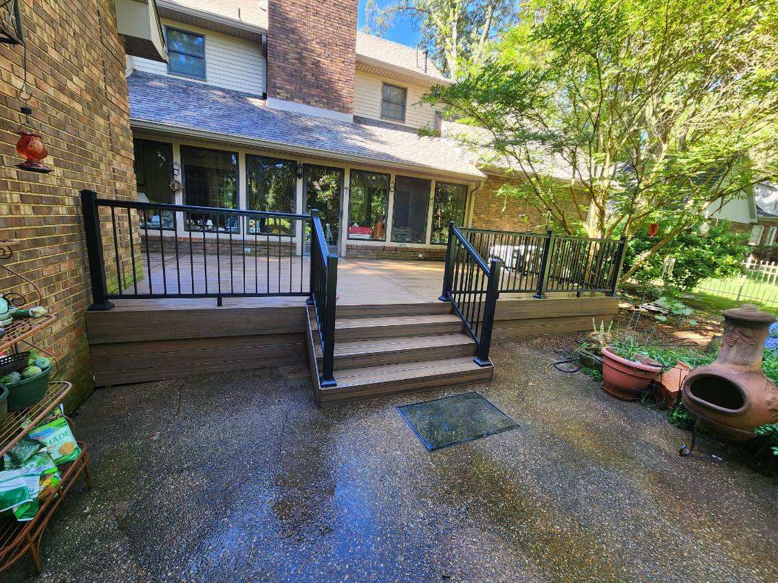There is a deck with stairs leading up to it in the backyard of a house.