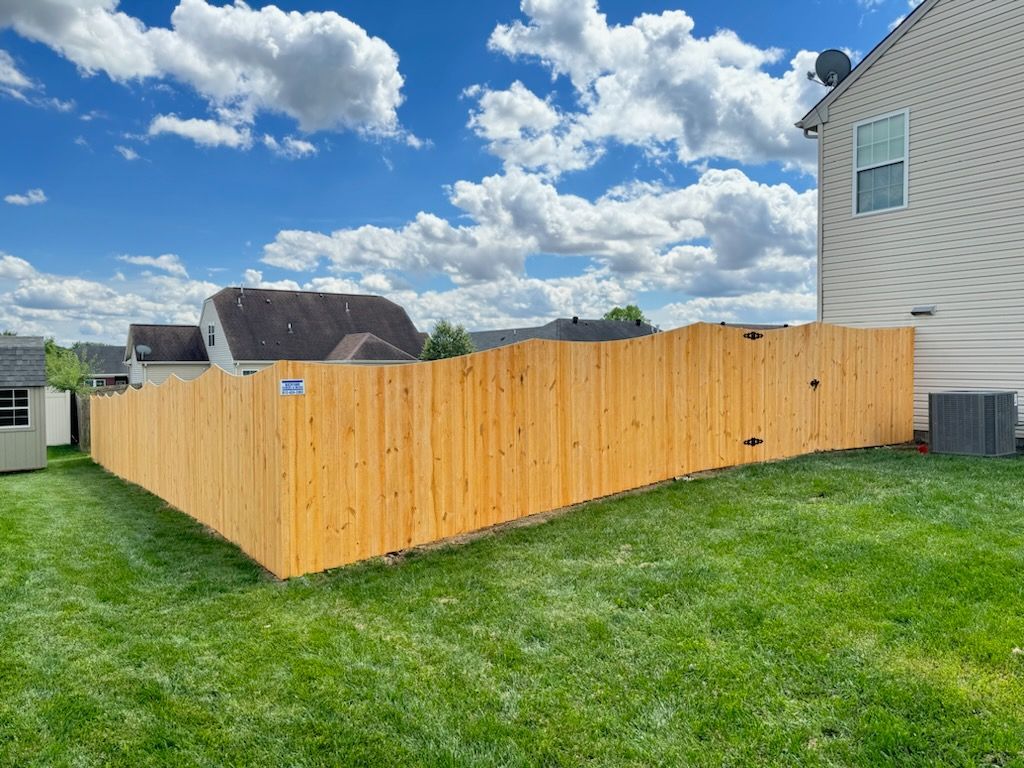 A wooden fence is in the backyard of a house.