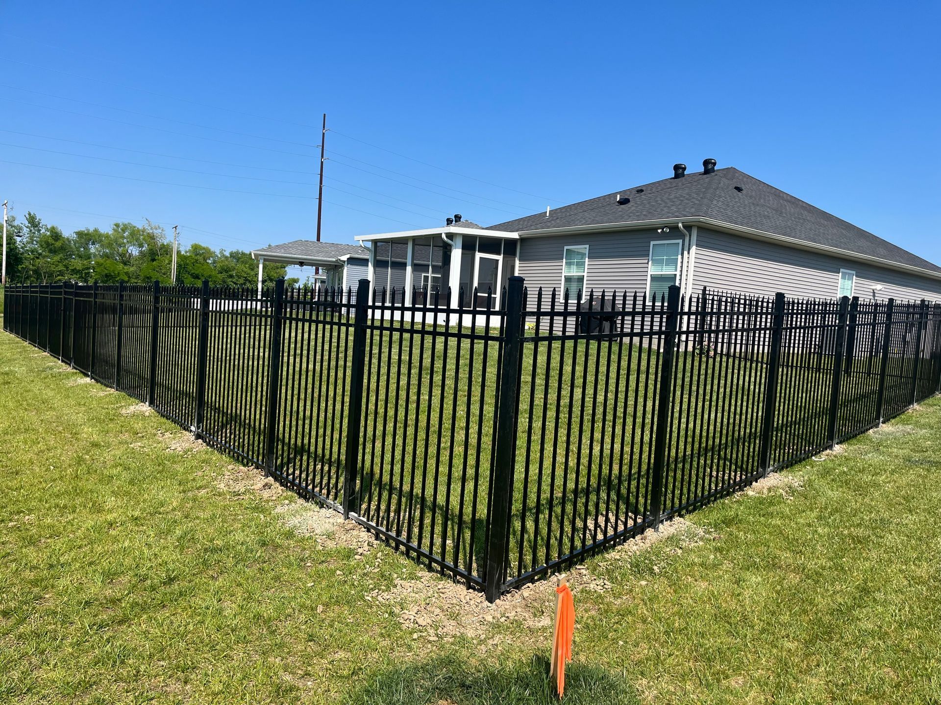 A black fence surrounds a house in a residential area.