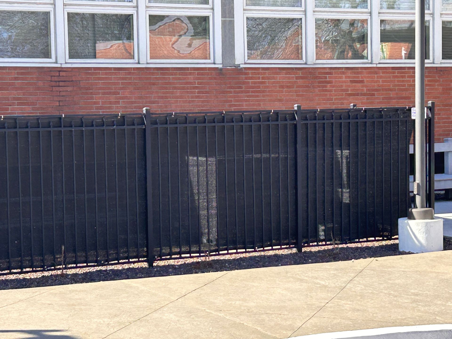 A black fence is in front of a brick building