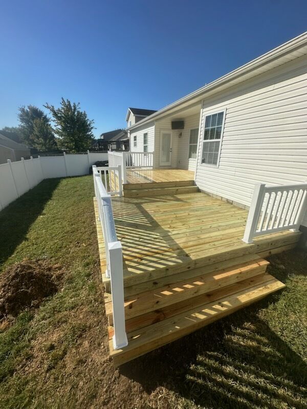 A white house with a wooden deck in front of it.
