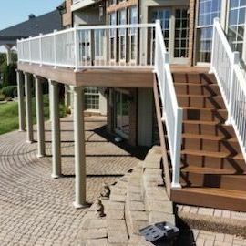 A large deck with stairs leading up to it and a white railing.