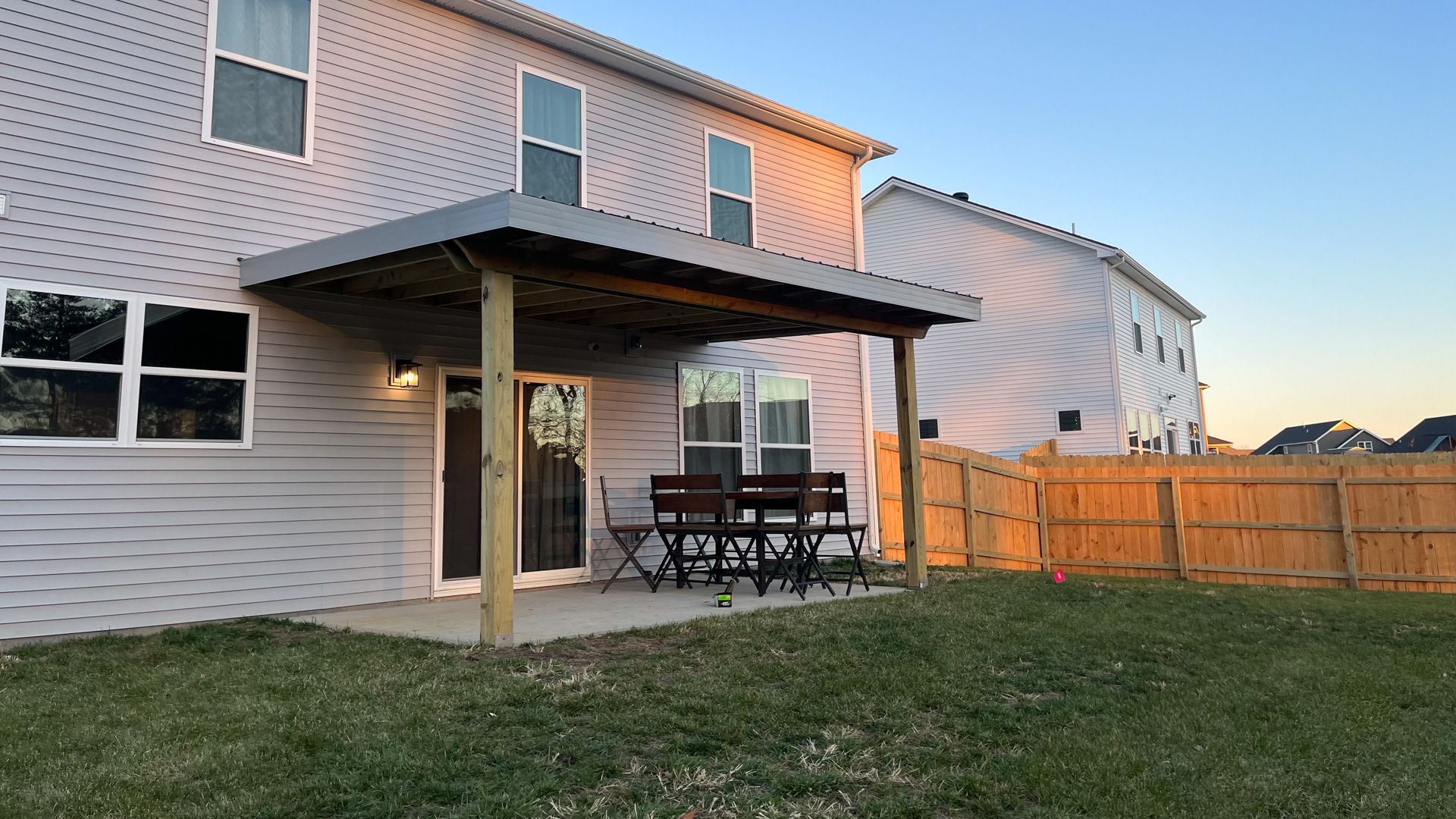 The backyard of a house with a patio and a wooden fence.