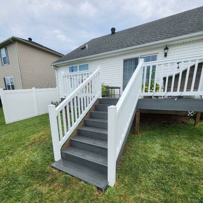 A white house with a deck and stairs leading up to it.