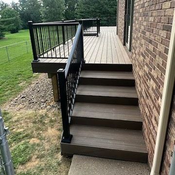 A deck with stairs leading up to it next to a brick building.