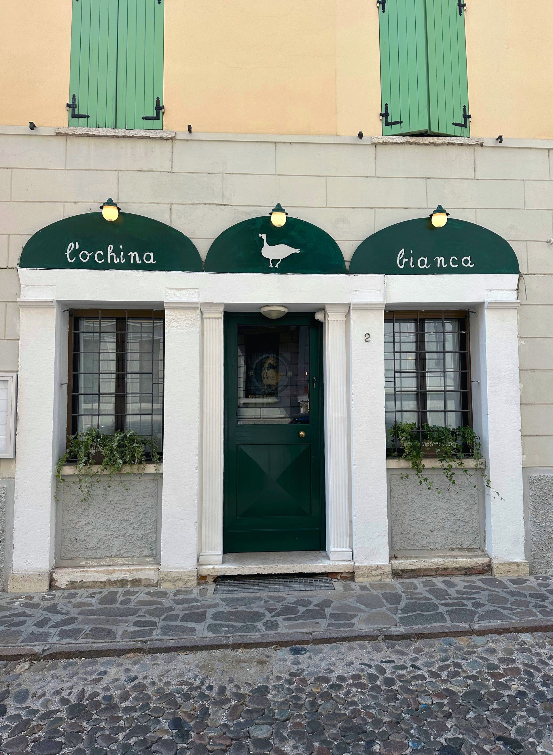 Un edificio con una porta verde e un cartello che dice bianca