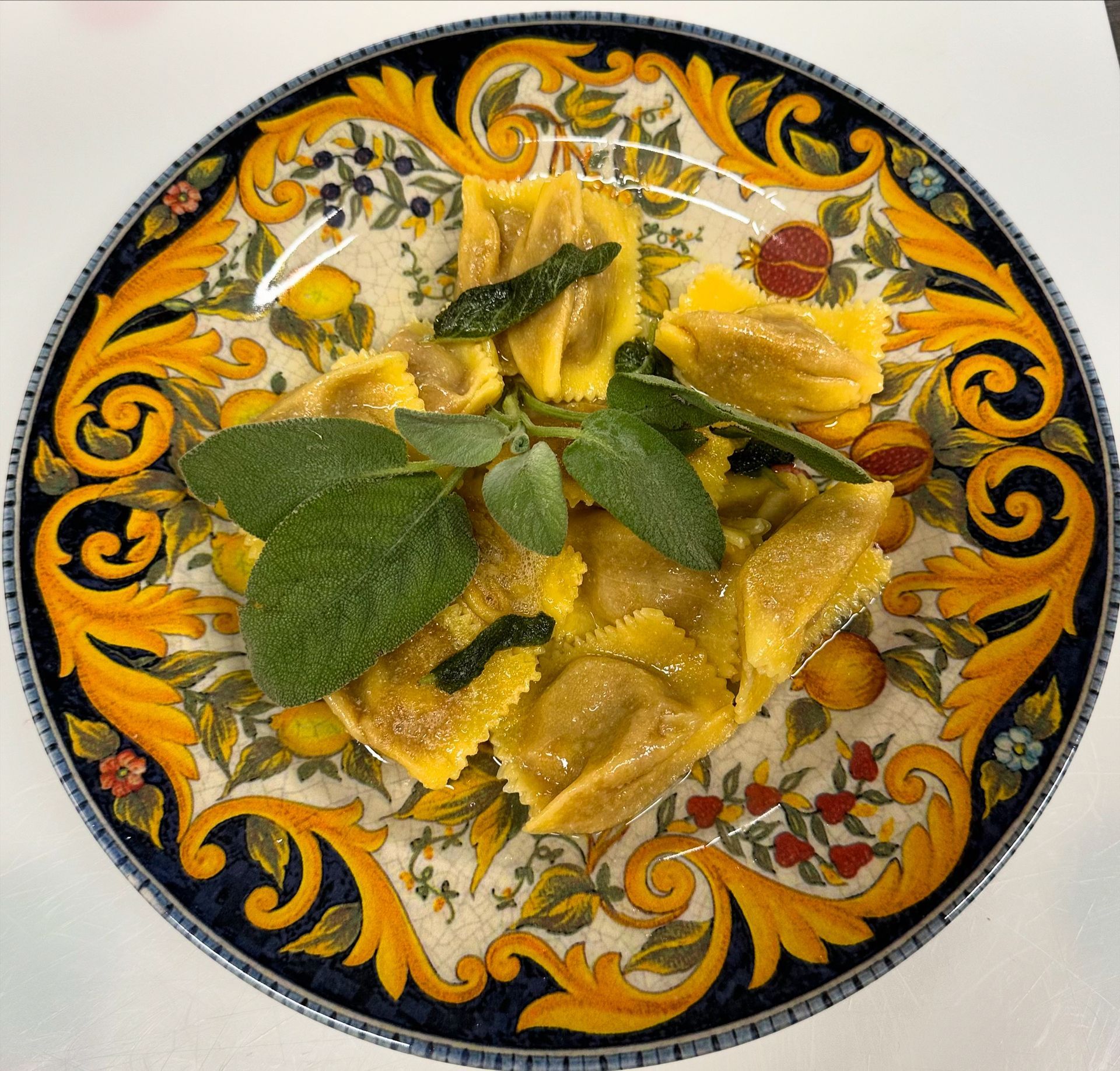 Un piatto di ravioli con salvia e olive sopra