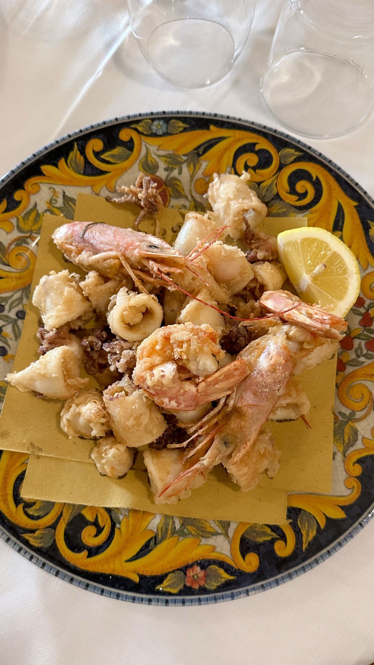 Un piatto di frutti di mare fritti con una fetta di limone su un tavolo.