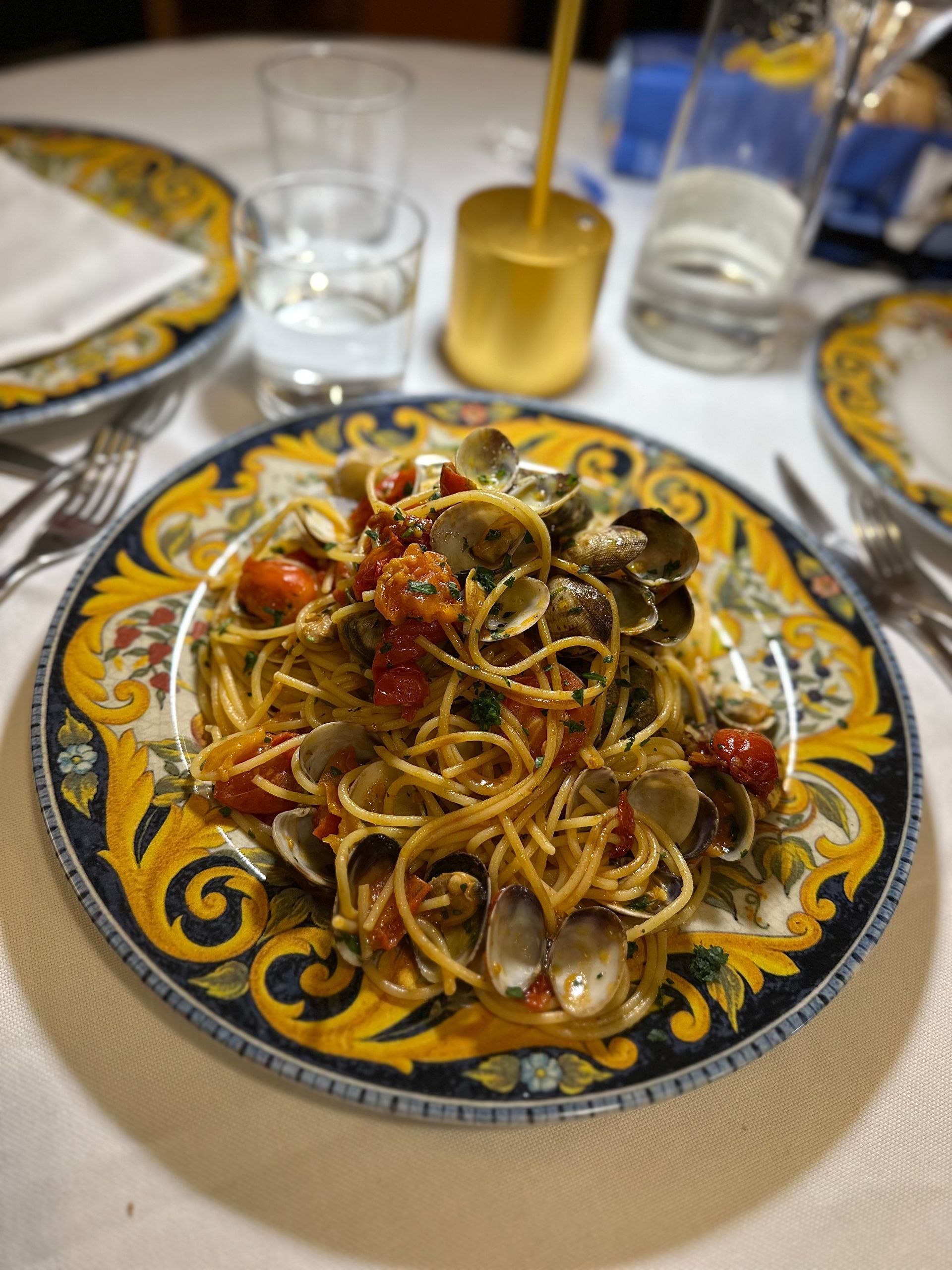 Un piatto di spaghetti con vongole e pomodori su un tavolo.