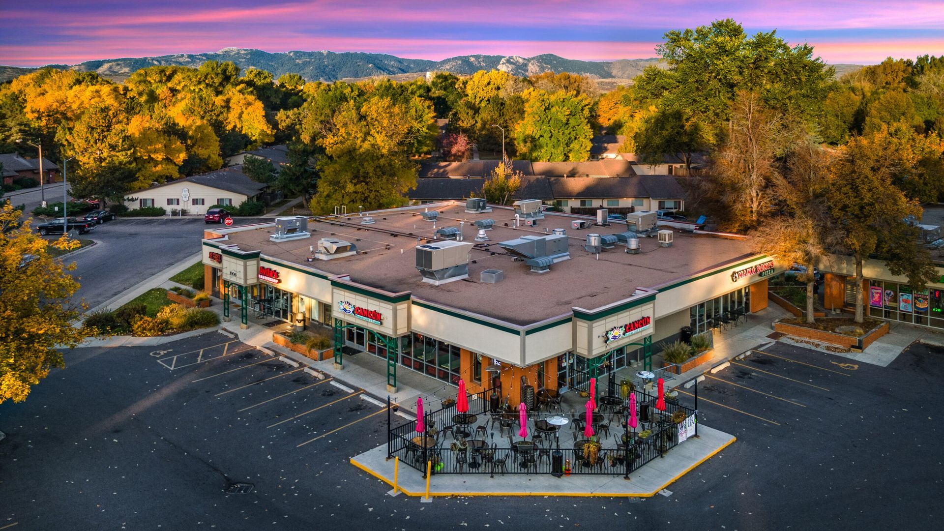 An aerial view of a restaurant surrounded by trees and a parking lot.