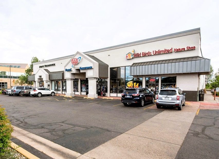 A row of cars are parked in front of a building.