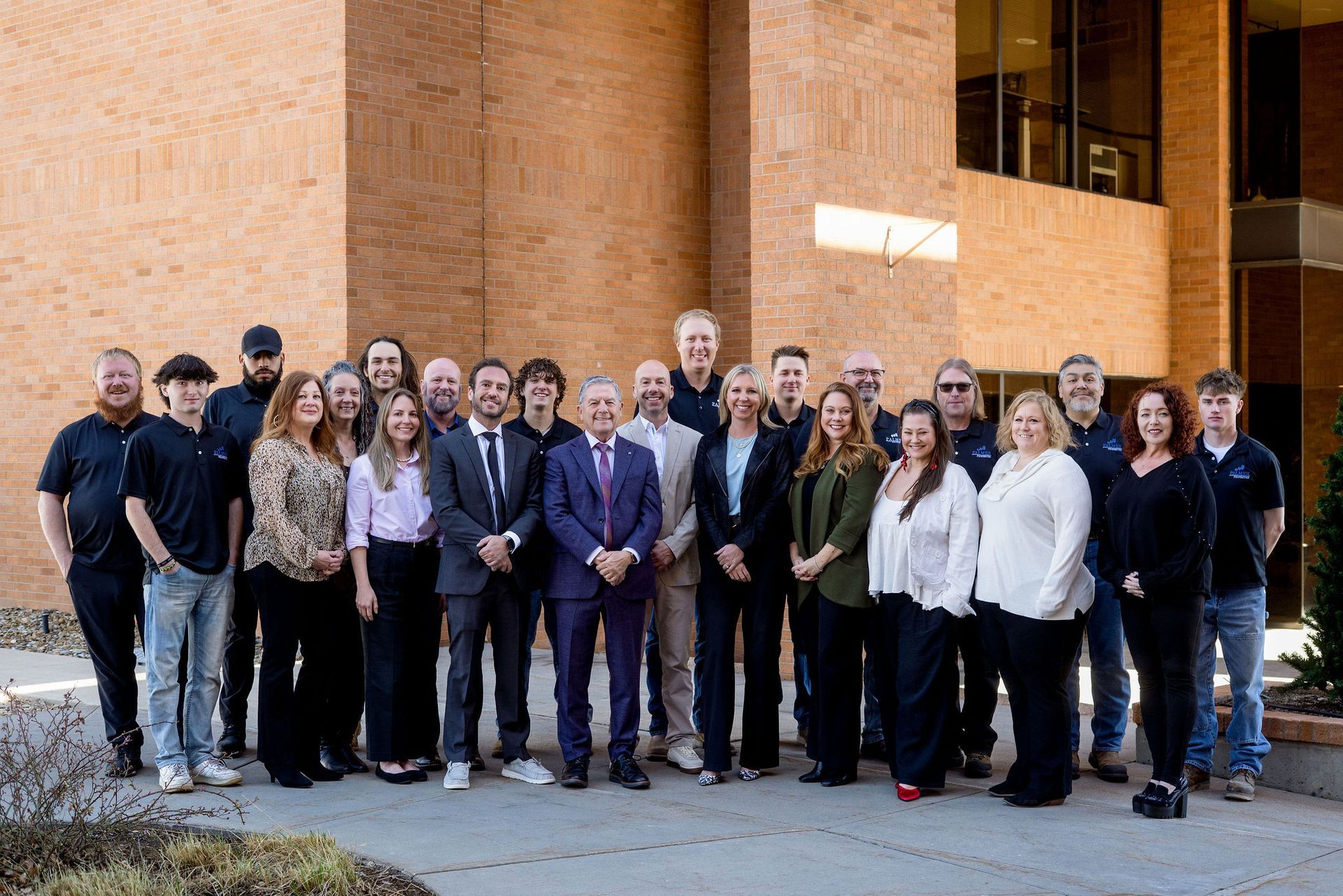 A group of people are posing for a picture in front of a brick building.