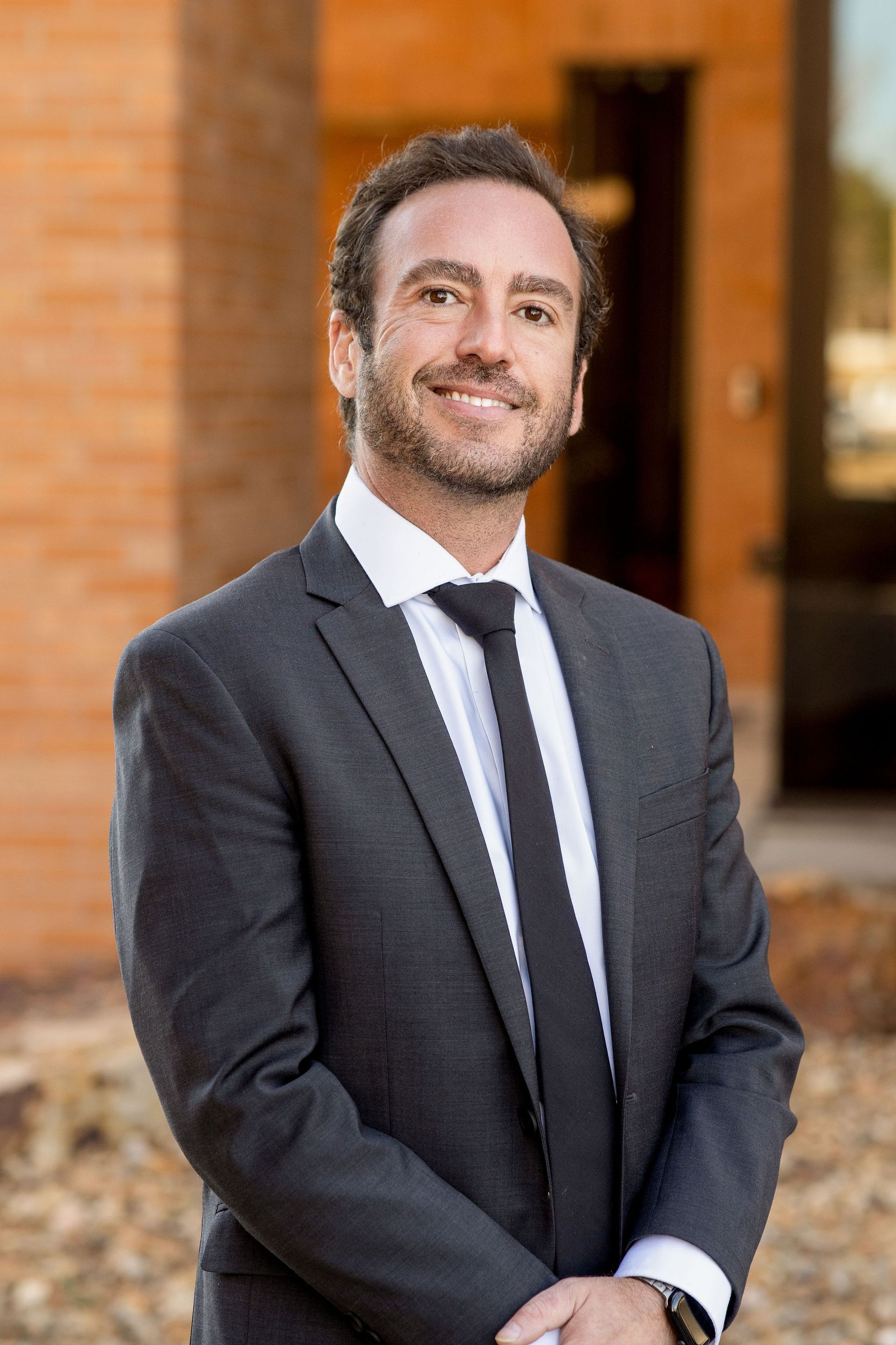 A man with a beard is wearing a suit and smiling for the camera.