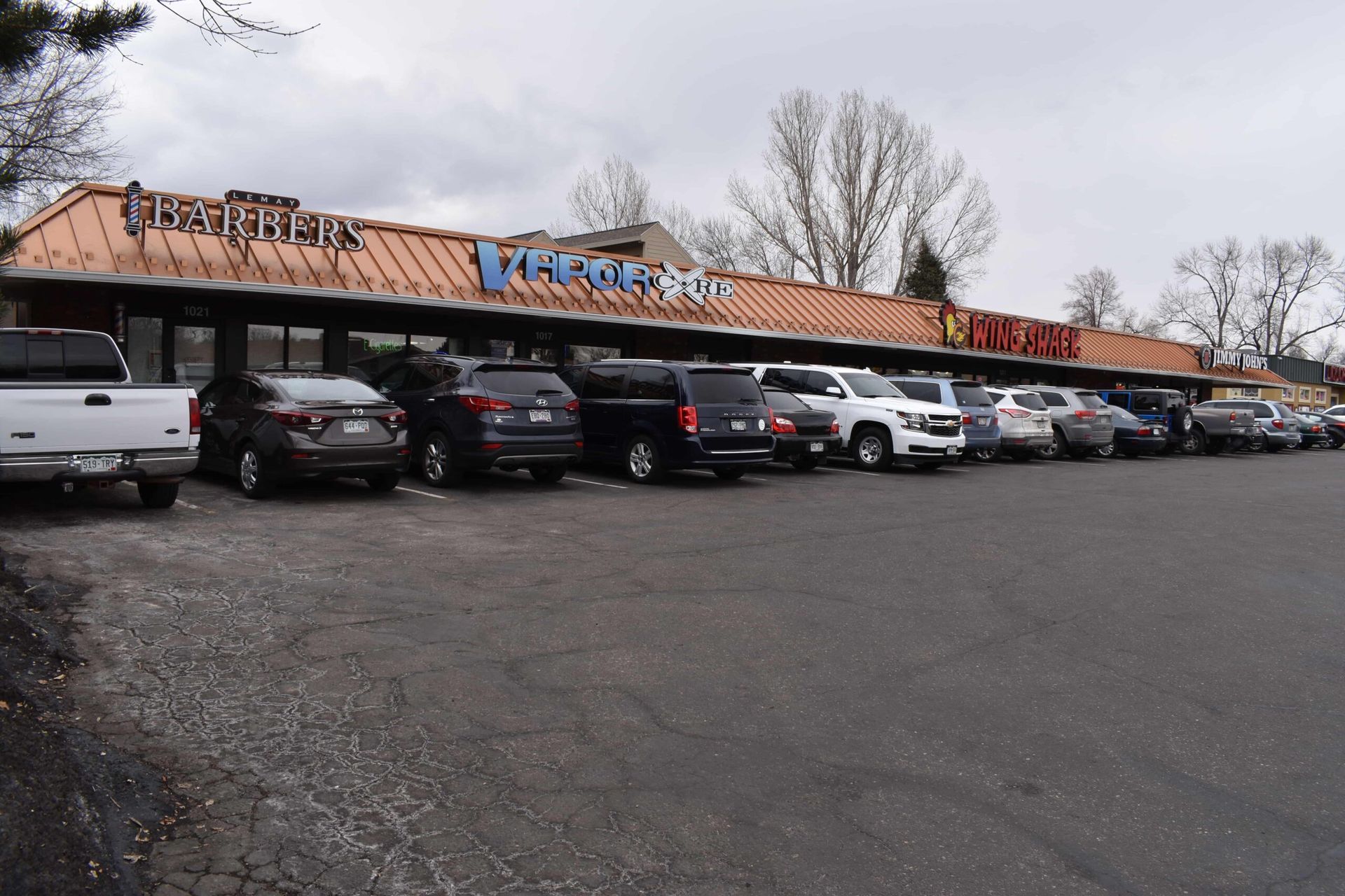 A row of cars are parked in front of a building that says trader joe 's