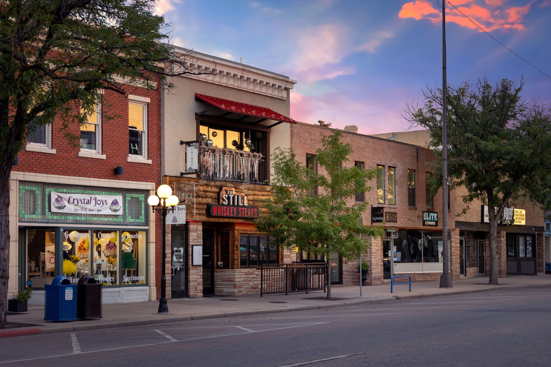 A row of buildings on a city street with a sunset in the background