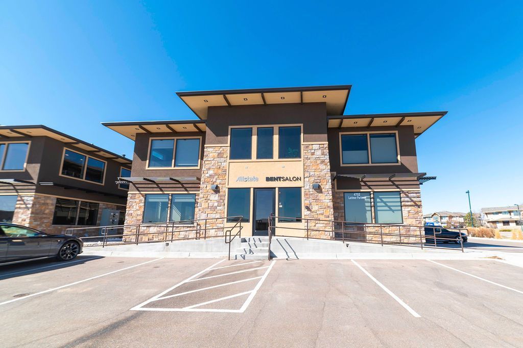 A large building with a lot of windows and a parking lot in front of it.