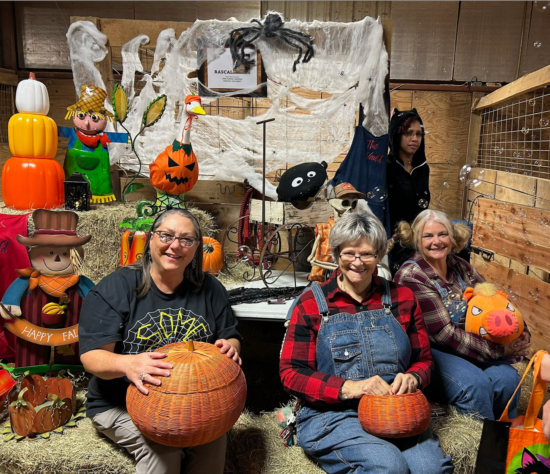 People posing with pumpkins at a Halloween display in a store, with spooky decorations behind them