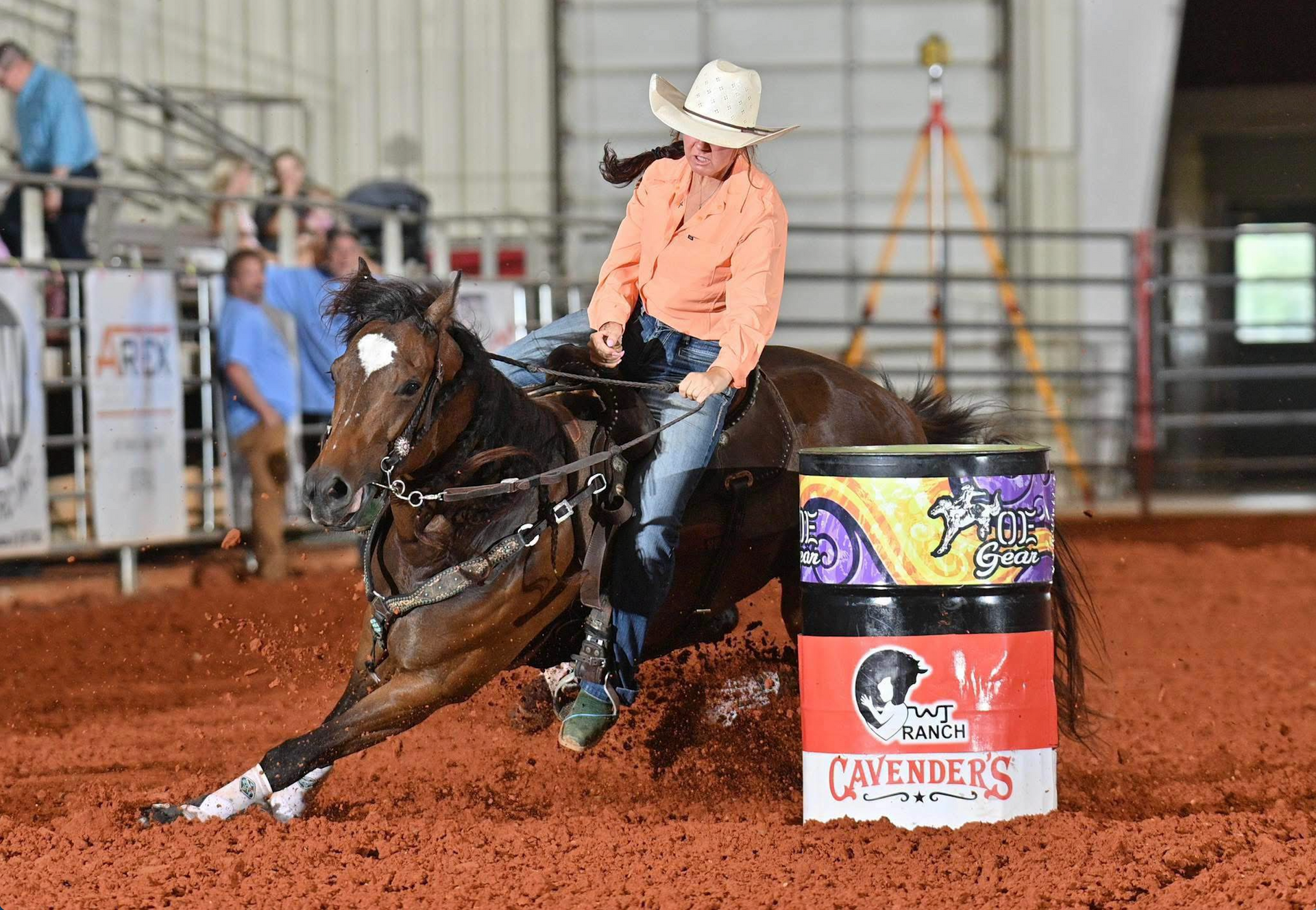 Horse and rider racing around a barrel in an indoor rodeo arena