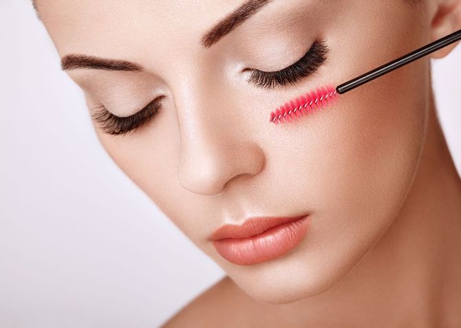 Eine Frau trägt mit einer Bürste Mascara auf ihre Wimpern auf.