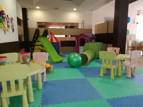 A children 's play area with tables and chairs and a slide.