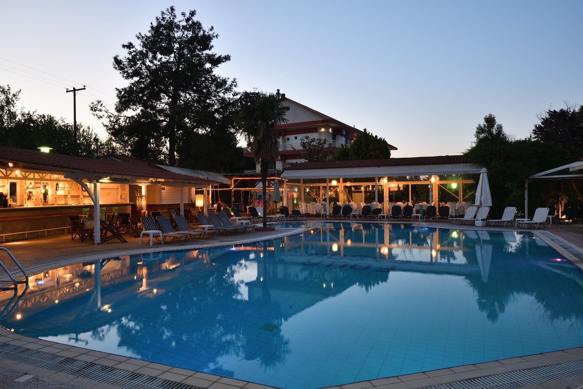 A large swimming pool with a restaurant in the background at night.