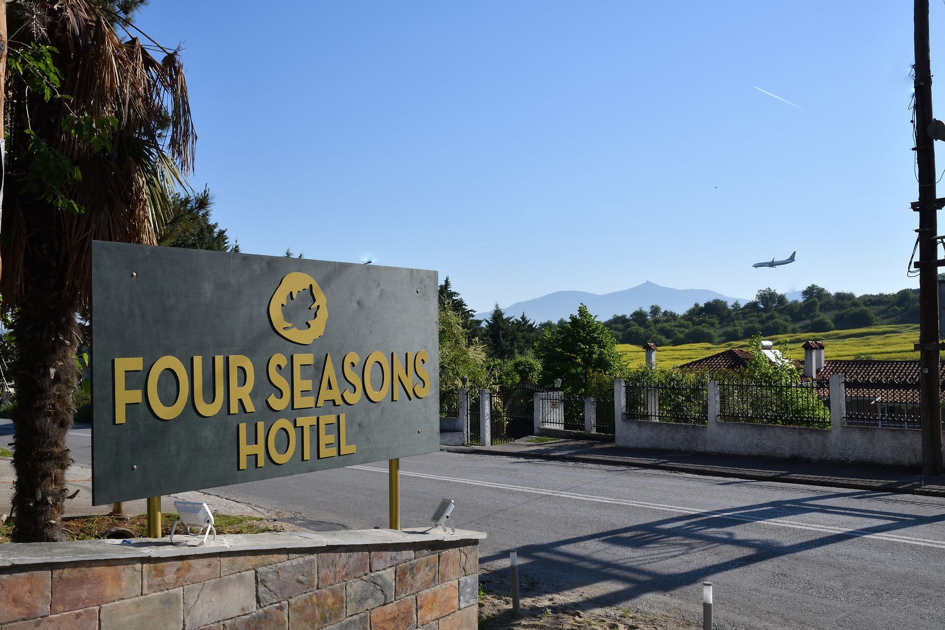 A four seasons hotel sign with a plane flying in the background