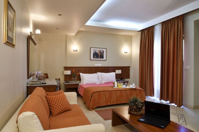 A hotel room with a couch a bed and a laptop